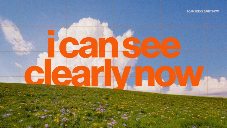 Bright blue sky with fluffy clouds above a vibrant green field filled with wildflowers, featuring the text "I can see clearly now."