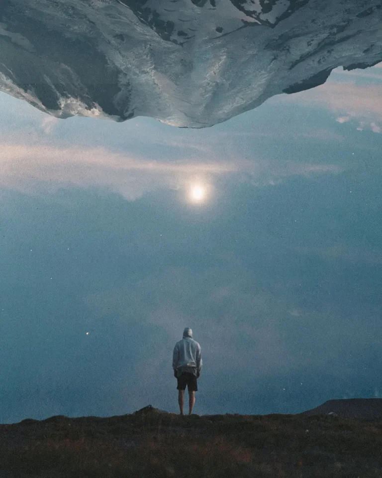 Individual standing under a night sky, reflecting solitude, and spiritual contemplation, with mountains upside-down above.