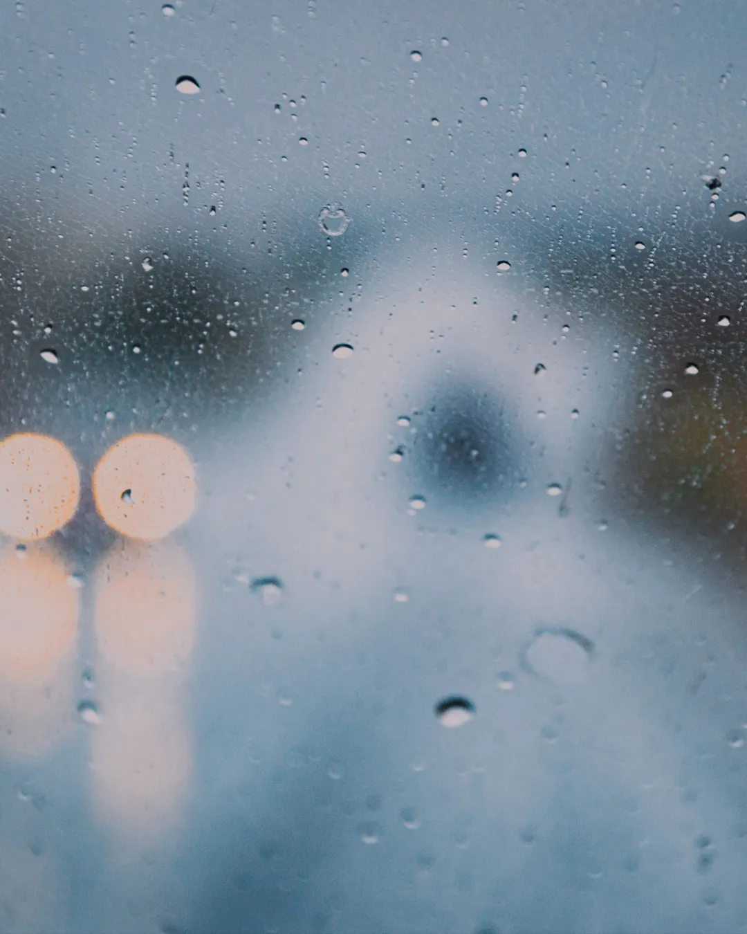 Raindrops on a window, symbolizing reflection and hope amid life's storms, inviting faith and community connection.