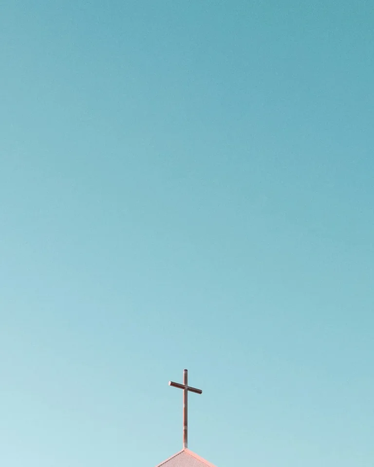 Cross atop a church against a clear blue sky, symbolizing faith, hope, and community in worship.