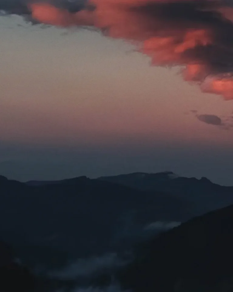 Serene mountains at dusk, with soft pink clouds reflecting hope and tranquility, inviting reflection and connection with faith.