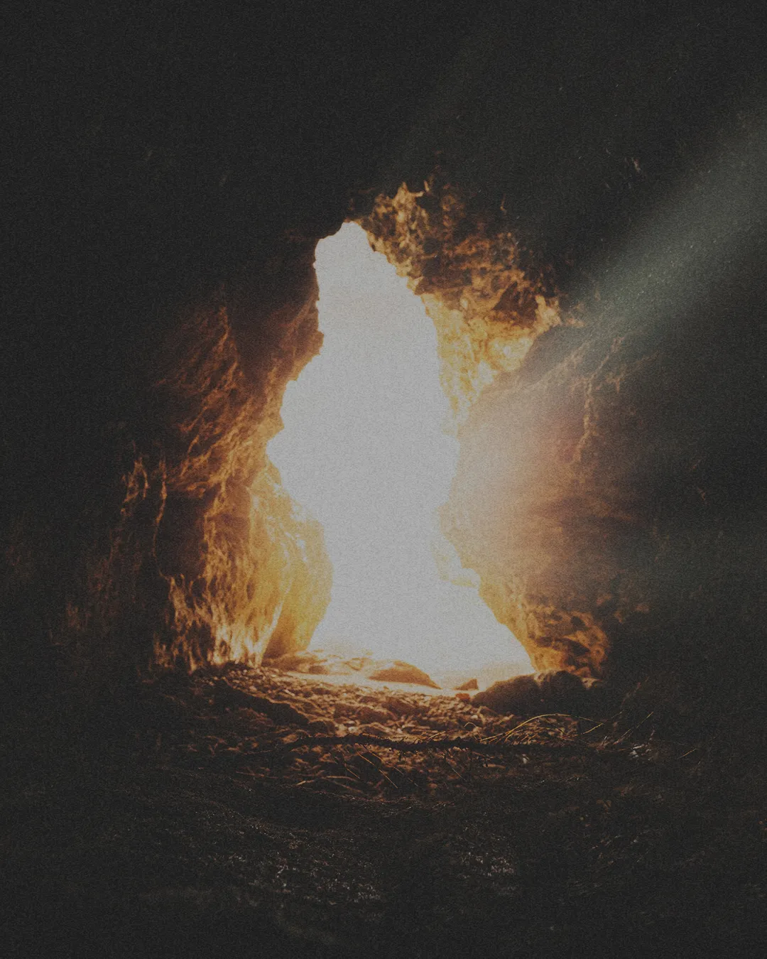 Light streams through a cave opening, symbolizing hope, resurrection, and the promise of new beginnings in faith.