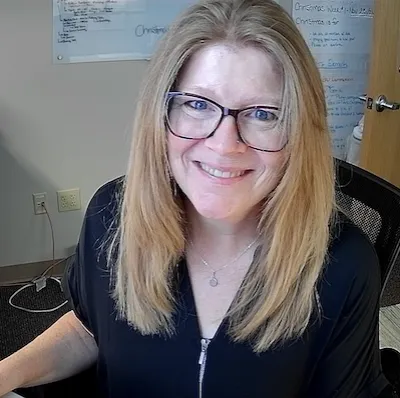Smiling person in an office setting with a whiteboard, fostering a welcoming and community-focused church environment.